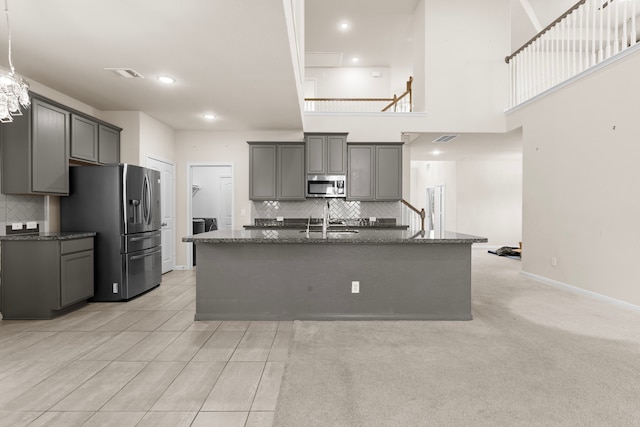 7603 Millstone Trail Ln, Richmond, TX 77469 - kitchen with appliances with stainless steel finishes, tasteful backsplash, gray cabinetry, a kitchen island with sink, and dark stone counters