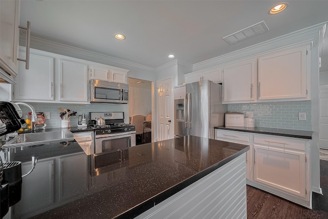 18206 Lake Bend Dr, Houston, TX 77084 - kitchen with appliances with stainless steel finishes, white cabinetry, tasteful backsplash, ornamental molding, and recessed lighting