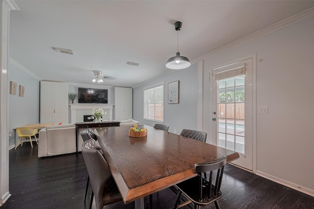 18206 Lake Bend Dr, Houston, TX 77084 - dining space with crown molding, dark wood-style flooring, baseboards, a ceiling fan, and a fireplace