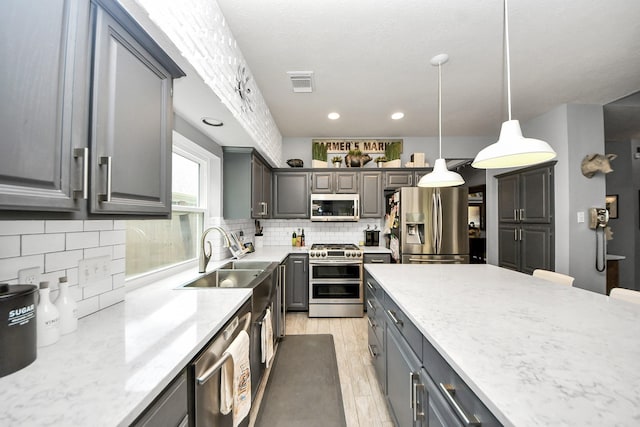 8910 Burleson Ct, Houston, TX 77064 - kitchen featuring appliances with stainless steel finishes, gray cabinets, a sink, decorative backsplash, and pendant lighting