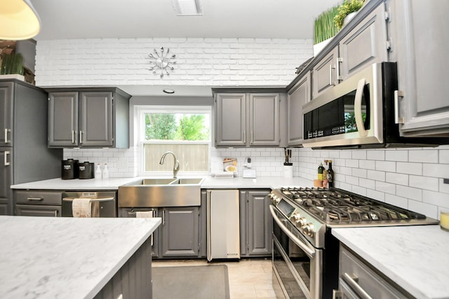 8910 Burleson Ct, Houston, TX 77064 - kitchen featuring stainless steel appliances, a sink, gray cabinetry, and backsplash