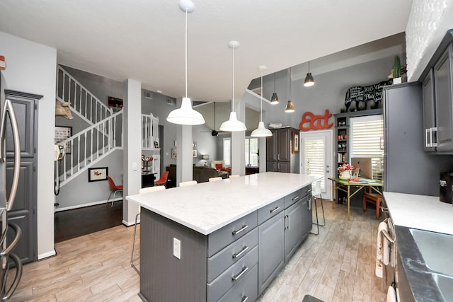 8910 Burleson Ct, Houston, TX 77064 - kitchen with gray cabinetry, light wood-style floors, a center island, and a kitchen bar