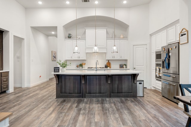 23603 Bottlebrush Terrace Trl, Katy, TX 77493 - kitchen featuring appliances with stainless steel finishes, a towering ceiling, light countertops, tasteful backsplash, and wood finished floors