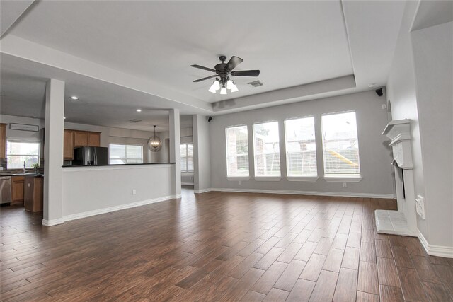 3014 Brahman Dr, Manvel, TX 77578 - unfurnished living room featuring a ceiling fan, dark wood-style floors, baseboards, a tray ceiling, and recessed lighting