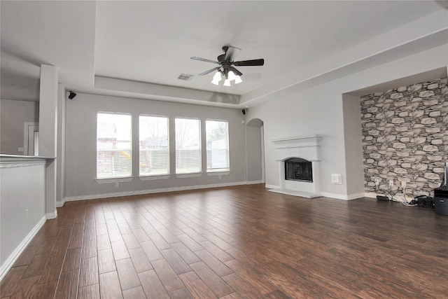 3014 Brahman Dr, Manvel, TX 77578 - unfurnished living room with ceiling fan, wood finished floors, a tray ceiling, a fireplace with raised hearth, and baseboards