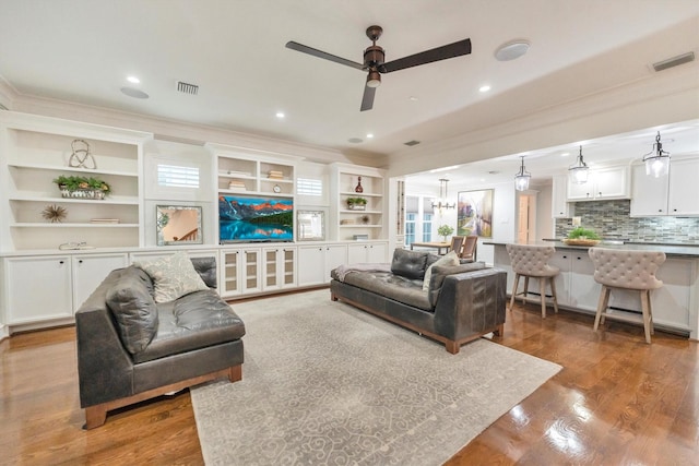 970 W 41st St, Houston, TX 77018 - living room with a ceiling fan, ornamental molding, wood finished floors, a chandelier, and built in shelves