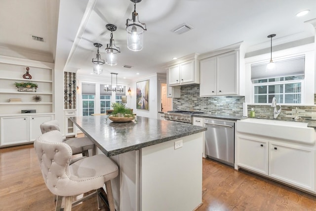 970 W 41st St, Houston, TX 77018 - kitchen featuring stainless steel dishwasher, a sink, backsplash, wood finished floors, and a center island