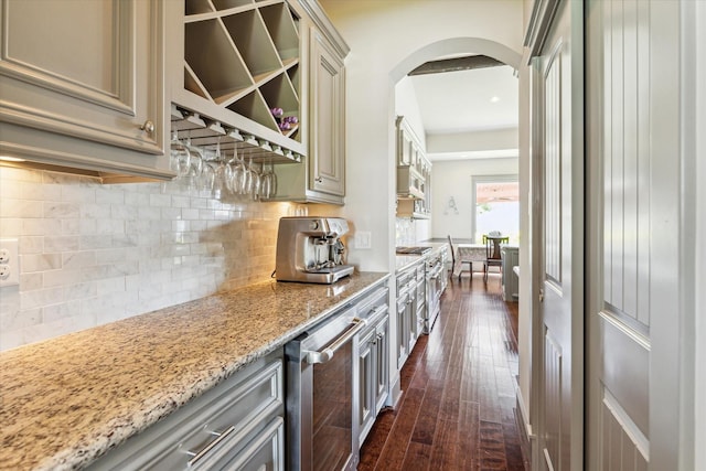 1243 Cheshire Ln, Houston, TX 77018 - kitchen with cream cabinetry, arched walkways, dark wood-style floors, decorative backsplash, and light stone counters