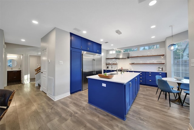 18 Heather Wisp Ct, Spring, TX 77381 - kitchen featuring blue cabinets, built in refrigerator, light countertops, wall chimney range hood, and recessed lighting