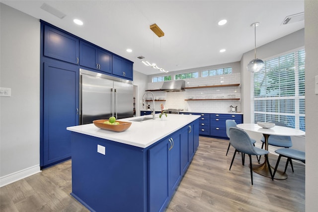 18 Heather Wisp Ct, Spring, TX 77381 - kitchen with appliances with stainless steel finishes, blue cabinets, a sink, light wood-type flooring, and light countertops