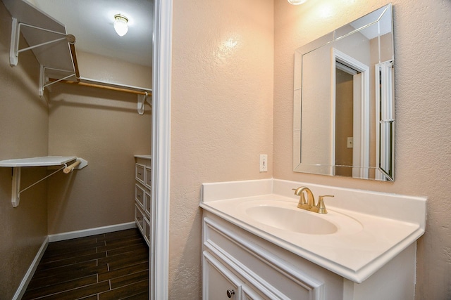 1117 King St, Houston, TX 77022 - bathroom featuring vanity, a spacious closet, wood finished floors, and baseboards