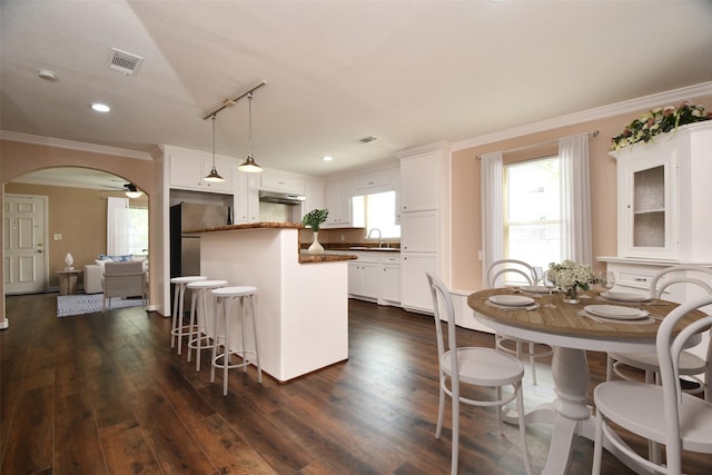 1117 King St, Houston, TX 77022 - kitchen with a breakfast bar area, a center island, crown molding, dark wood-style flooring, and white cabinetry