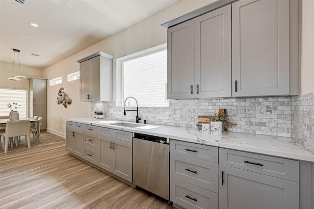 2905 Nagle St, Houston, TX 77004 - kitchen with stainless steel dishwasher, gray cabinets, a sink, tasteful backsplash, and light stone countertops