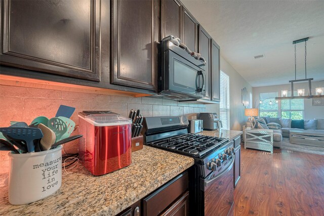 4323 N Vineyard Mdw Ln, Katy, TX 77449 - kitchen with gas stove, black microwave, wood finished floors, open floor plan, and backsplash