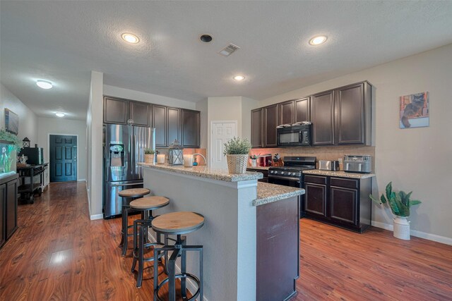 4323 N Vineyard Mdw Ln, Katy, TX 77449 - kitchen with appliances with stainless steel finishes, a breakfast bar, decorative backsplash, dark wood finished floors, and dark brown cabinetry