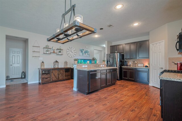 4323 N Vineyard Mdw Ln, Katy, TX 77449 - kitchen with wood finished floors, a sink, a textured ceiling, a kitchen island, and stainless steel appliances