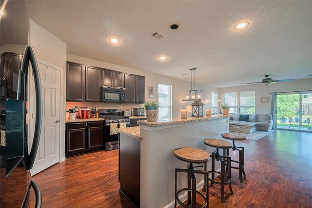 4323 N Vineyard Mdw Ln, Katy, TX 77449 - kitchen featuring black microwave, stainless steel gas range oven, freestanding refrigerator, dark wood-type flooring, and healthy amount of natural light
