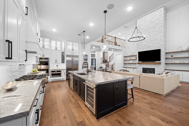 2105 Bennet Ct, Conroe, TX 77384 - kitchen with a sink, beverage cooler, white cabinetry, wood finished floors, and a fireplace