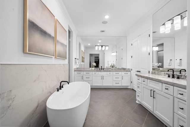 2105 Bennet Ct, Conroe, TX 77384 - full bathroom with crown molding, a soaking tub, two vanities, tile patterned flooring, and tile walls