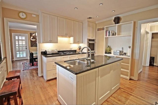 1216 S Shepherd Dr, Houston, TX 77019 - kitchen featuring a sink, ornamental molding, open shelves, light wood-style flooring, and an island with sink
