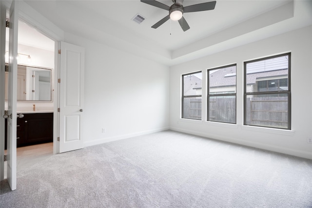 829 Laguna Green Ln, Katy, TX 77493 - empty room with light carpet, ceiling fan, a tray ceiling, and baseboards