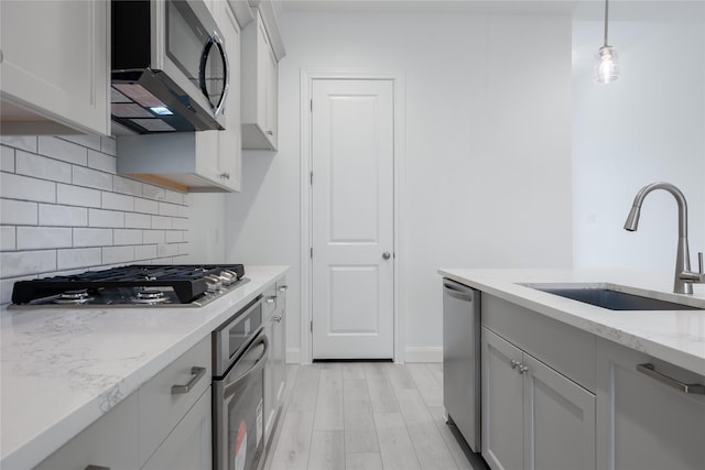 829 Laguna Green Ln, Katy, TX 77493 - kitchen with stainless steel appliances, a sink, backsplash, light stone countertops, and hanging light fixtures