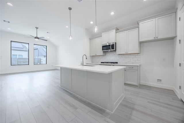 829 Laguna Green Ln, Katy, TX 77493 - kitchen with stainless steel microwave, a sink, backsplash, light wood-style floors, and a ceiling fan