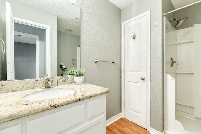 105 Wisteria St, Lake Jackson, TX 77566 - bathroom with wood finished floors, vanity, a shower, a textured wall, and a textured ceiling