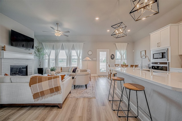 21450 Petherton Dr, Tomball, TX 77375 - living room featuring a chandelier, healthy amount of natural light, light wood-type flooring, recessed lighting, and a tiled fireplace