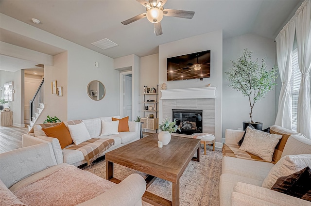 21450 Petherton Dr, Tomball, TX 77375 - living room with a ceiling fan, light wood-style floors, a tile fireplace, stairway, and baseboards