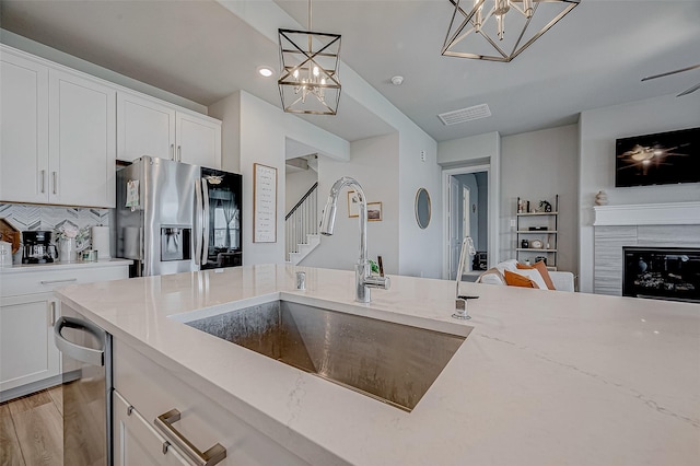 21450 Petherton Dr, Tomball, TX 77375 - kitchen with stainless steel refrigerator with ice dispenser, a chandelier, a sink, open floor plan, and light stone countertops