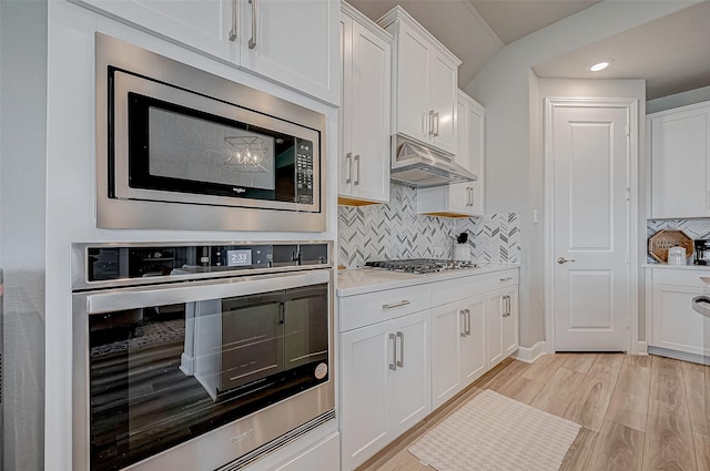 21450 Petherton Dr, Tomball, TX 77375 - kitchen with stainless steel appliances, under cabinet range hood, white cabinets, tasteful backsplash, and recessed lighting