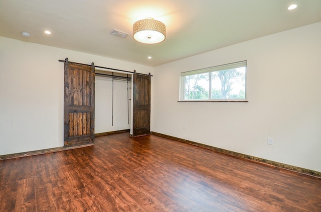 36615 Maverick Rd, Simonton, TX 77485 - unfurnished bedroom featuring dark wood-type flooring, a barn door, recessed lighting, and baseboards
