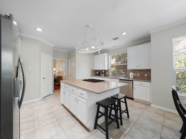 23647 Litchfield Bend Ln, Katy, TX 77494 - kitchen featuring appliances with stainless steel finishes, tasteful backsplash, healthy amount of natural light, a kitchen island, and ornamental molding