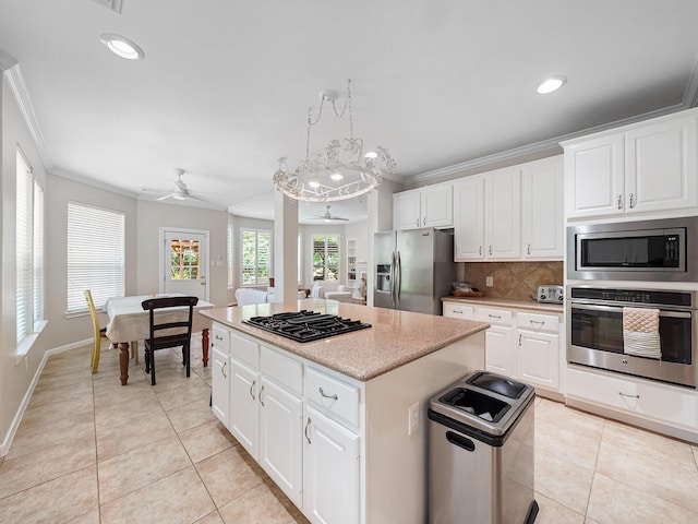 23647 Litchfield Bend Ln, Katy, TX 77494 - kitchen with stainless steel appliances, crown molding, a ceiling fan, light tile patterned floors, and a kitchen island