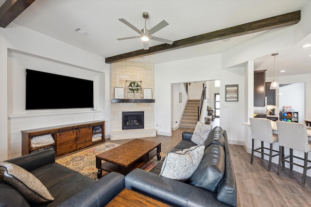 1685 Daylight Lake Dr, Katy, TX 77493 - living room featuring ceiling fan, wood finished floors, beam ceiling, stairs, and a stone fireplace