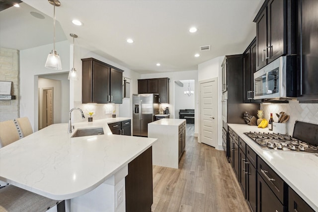 1685 Daylight Lake Dr, Katy, TX 77493 - kitchen with appliances with stainless steel finishes, a sink, light wood-style floors, a kitchen island, and decorative backsplash