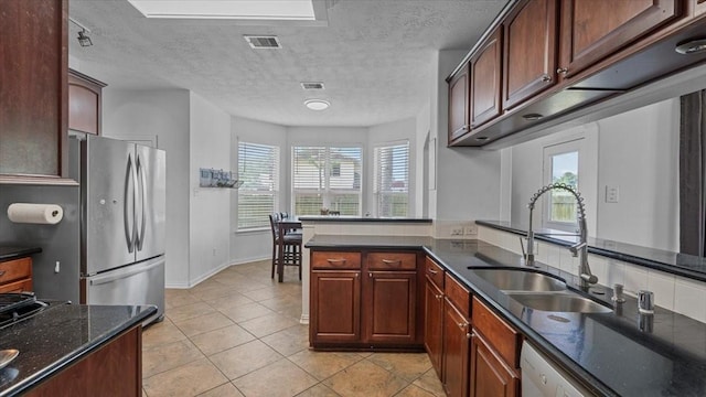 19603 Pitchstone Dr, Tomball, TX 77377 - kitchen with freestanding refrigerator, a sink, white dishwasher, light tile patterned floors, and dark stone countertops