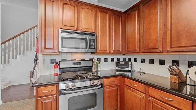 19603 Pitchstone Dr, Tomball, TX 77377 - kitchen featuring stainless steel appliances, tasteful backsplash, dark stone countertops, and brown cabinetry