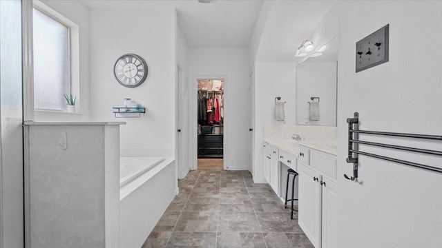 19603 Pitchstone Dr, Tomball, TX 77377 - bathroom with vanity, a bath, a spacious closet, stone finish flooring, and baseboards