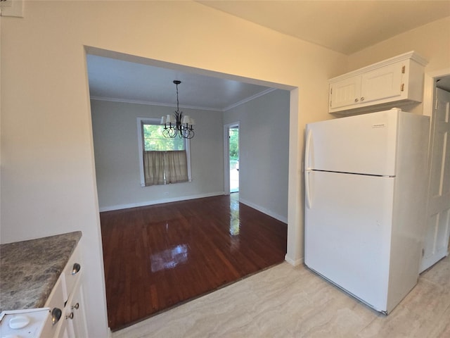 301 Harold St, Crockett, TX 75835 - kitchen featuring freestanding refrigerator, white cabinetry, crown molding, light wood-style floors, and a chandelier