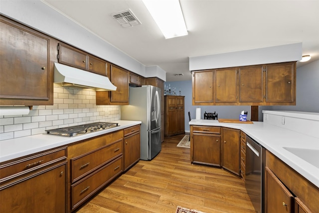 613 Bolling Green Dr, Wharton, TX 77488 - kitchen featuring under cabinet range hood, appliances with stainless steel finishes, light wood-type flooring, and light countertops