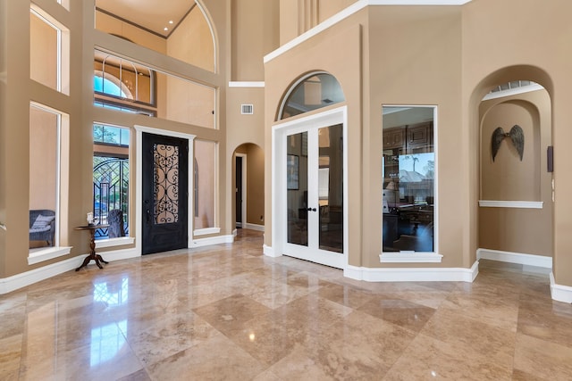 15818 Conners Ace Dr, Spring, TX 77379 - foyer featuring arched walkways, marble tiled flooring, a towering ceiling, baseboards, and french doors