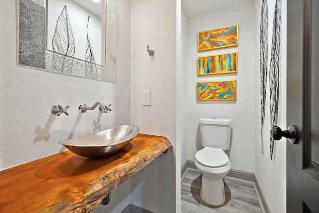 7 Woodstone St, Houston, TX 77024 - half bath featuring a sink, baseboards, toilet, and wood finished floors