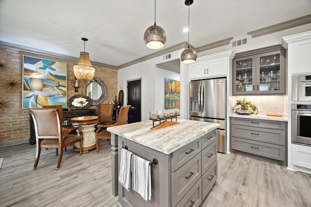 7 Woodstone St, Houston, TX 77024 - kitchen featuring appliances with stainless steel finishes, gray cabinets, brick wall, glass insert cabinets, and light wood-type flooring