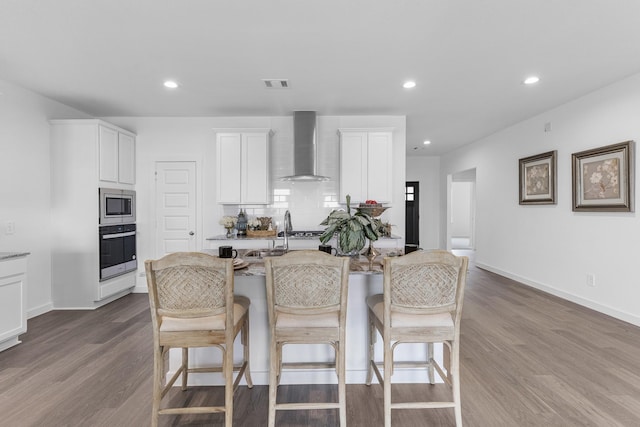 5302 Allen Cay, Texas City, TX 77590 - kitchen featuring wall chimney range hood, appliances with stainless steel finishes, a kitchen bar, dark wood-style floors, and recessed lighting