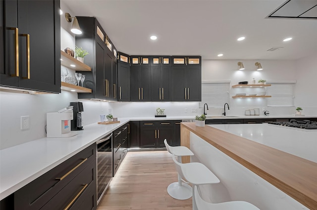 4434 Sarong Dr, Houston, TX 77096 - kitchen featuring open shelves, wine cooler, light countertops, light wood-style flooring, and gas stovetop