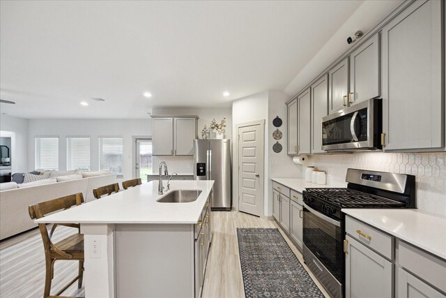 3710 Birtley Bend Way, Fulshear, TX 77441 - kitchen featuring gray cabinets, appliances with stainless steel finishes, a sink, open floor plan, and a kitchen bar