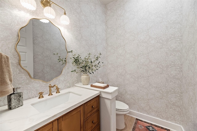 7851 Longhorn Trl, Fulshear, TX 77406 - bathroom with wallpapered walls, toilet, vanity, baseboards, and wood finished floors