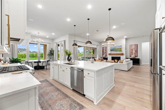 7851 Longhorn Trl, Fulshear, TX 77406 - kitchen with appliances with stainless steel finishes, a chandelier, a sink, a fireplace, and recessed lighting